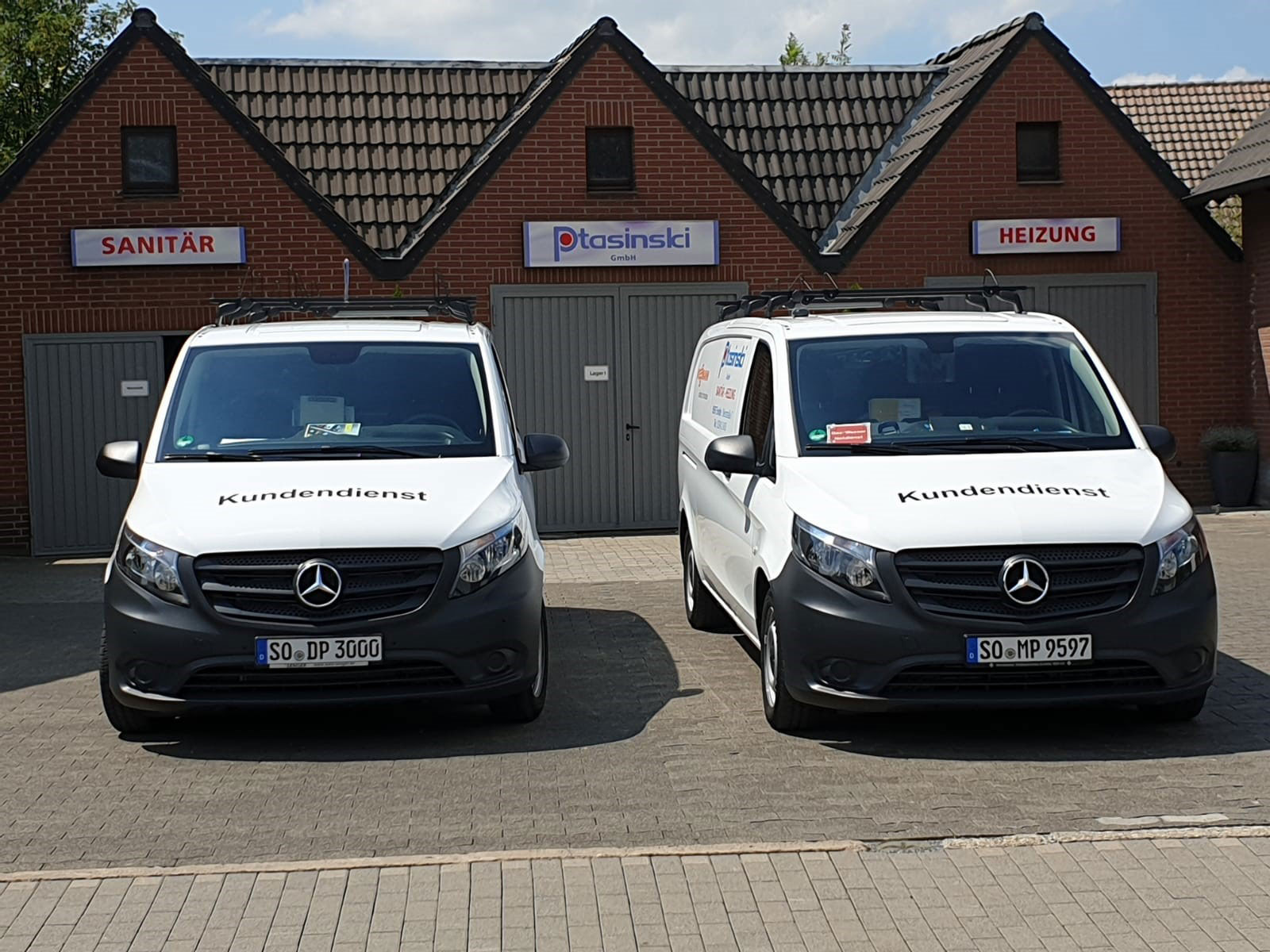 Zwei weiße Firmenwagen auf einem Parkplatz geparkt.