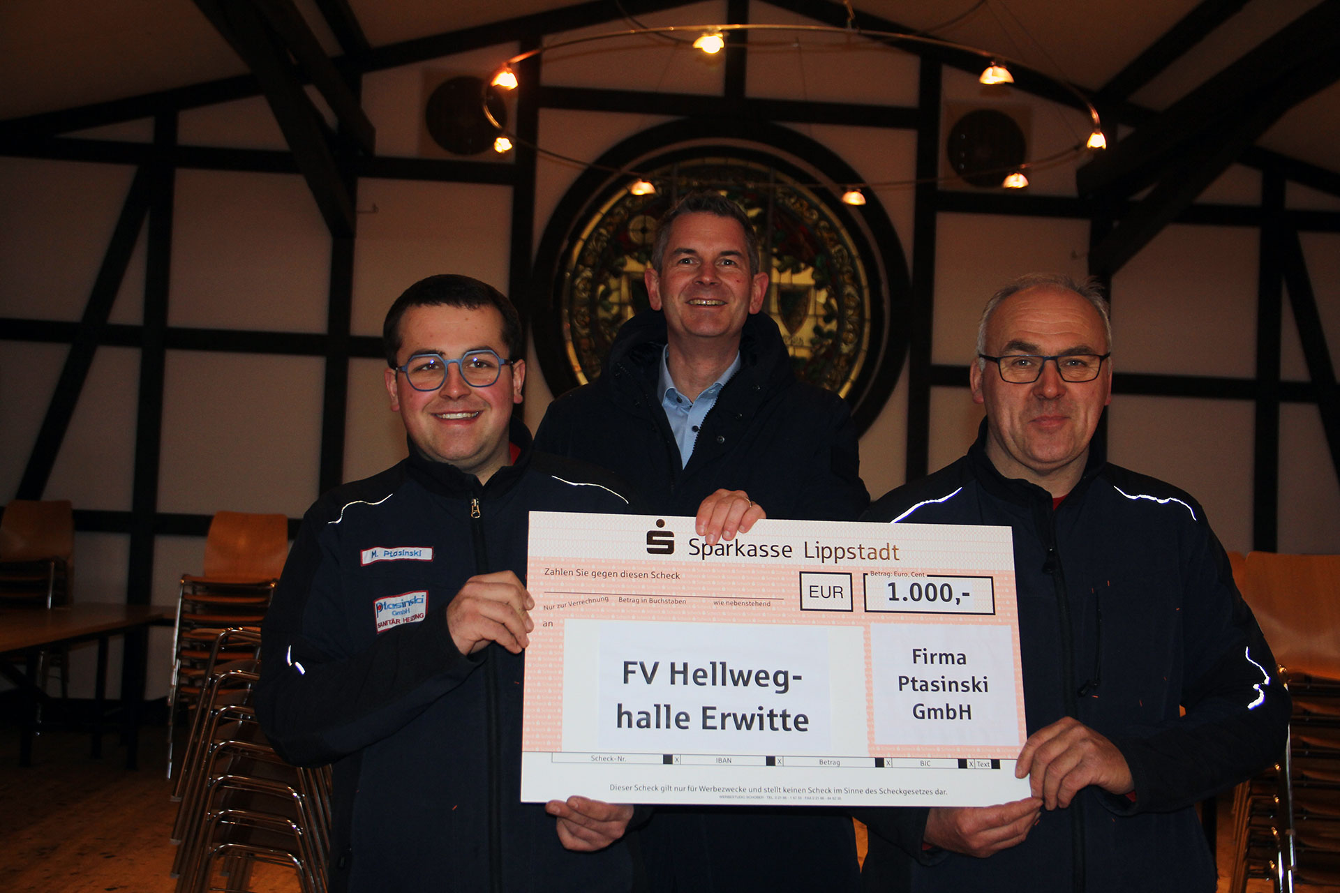 Drei Männer, die einen großen Scheck in Höhe von 1000€ halten.